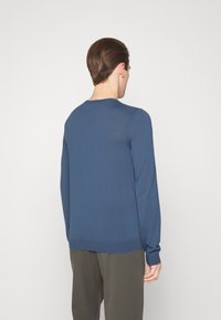 Modrý svetr s dlouhým rukávem a kulatým výstřihem, s žebrovanými manžetami, vyrobený z lehké pleteniny, představený z pohledu ze zad.