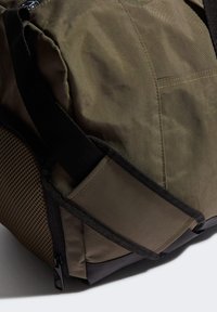 Borsa duffle verde oliva con superficie testurizzata, spallacci neri e dettagli in rete. Presenta una chiusura con zip e una base rinforzata per garantire durabilità.