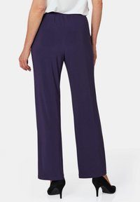 Lila, elastische Bundhosen mit geradem Schnitt, die eine glatte Textur und einen langen Schnitt aufweisen, kombiniert mit schwarzen High Heels.