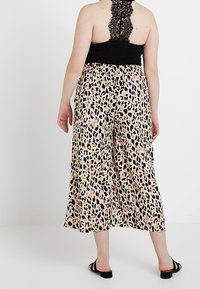 Kalhoty culotte s leopardím potiskem, vybavené elastickým pasem a černým krajkovým detailem na zadní části. Barvy zahrnují broskvovou, růžovou a žlutou.