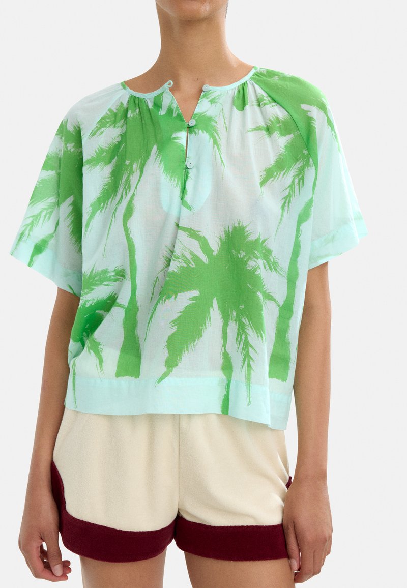 Lekki, krótki top z krótkimi rękawami w jasnoniebieskim kolorze, z zielonymi printami palm, z okrągłym dekoltem i zapięciem na guziki z przodu.