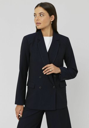 Blazer bleu marine à rayures fines en tissu tissé. Il présente un devant croisé, des revers à cran et deux poches avant.
