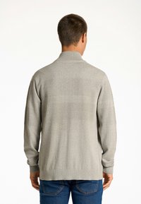 Grauer Strickpullover mit hohem Kragen, der ein strukturiertes Muster über den Schultern und dem Rücken aufweist. Lange Ärmel und lockere Passform.