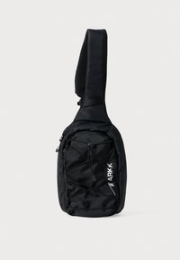 Borsa a tracolla nera con una tracolla testurizzata, dotata di una tasca frontale con zip e un design elastico incrociato. Il logo "ARKK" è stampato in bianco.