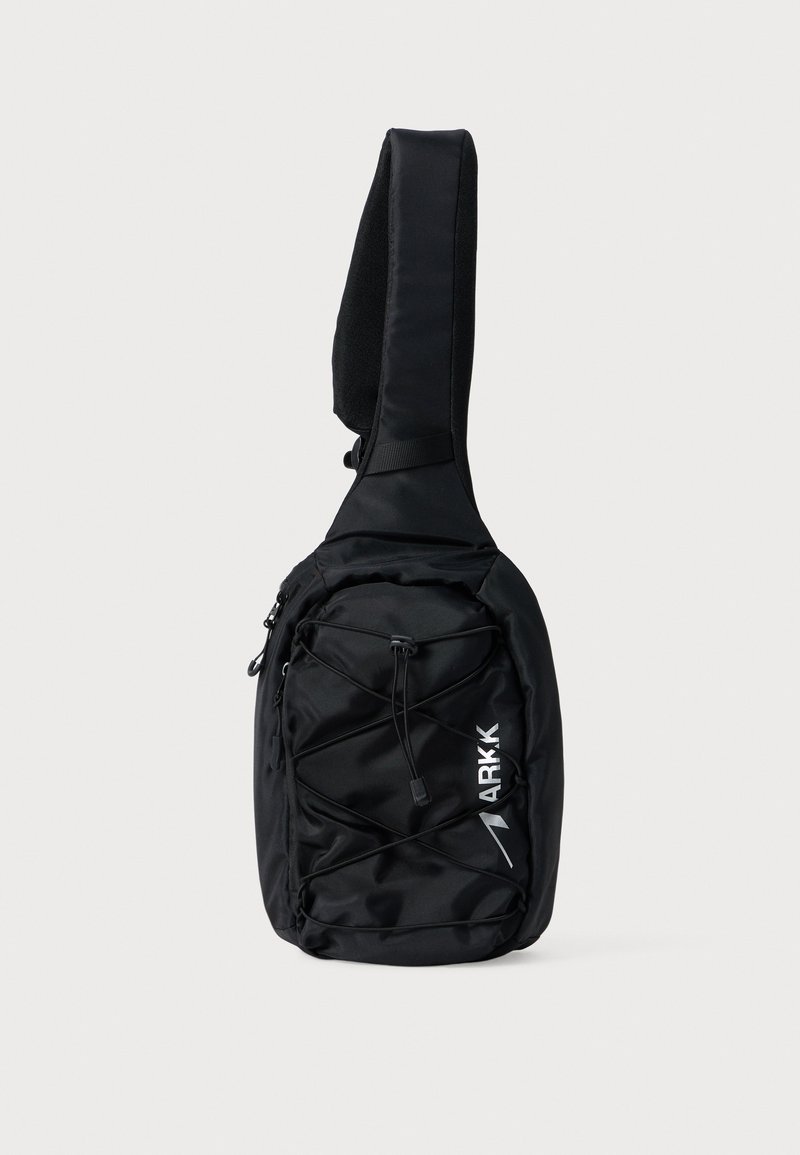 Borsa a tracolla nera con una tracolla testurizzata, dotata di una tasca frontale con zip e un design elastico incrociato. Il logo "ARKK" è stampato in bianco.