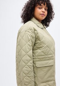 Ανοιχτοπράσινο μπουφάν με ραφή καπιτονέ, γιακά, πλαϊνή τσέπη και διαμάντι μοτίβο. Απαλή υφή υφάσματος και άνετη εφαρμογή.