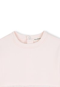 Haut rose clair à manches courtes. Matière en coton doux avec un col ras du cou côtelé et une étiquette au dos. Présente un détail en franges à l'ourlet.