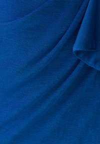 Sinine kangas peene tekstuuriga kudumisega, näidatud õrnade voltidega ja pehme langenemisega.