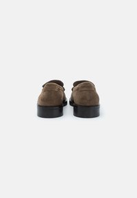 Braune Wildlederschuhe mit glatter Oberfläche, runder Zehenform und schwarzen Gummisohlen. Dezente Markierung auf der Rückseite. Rückansicht gezeigt.