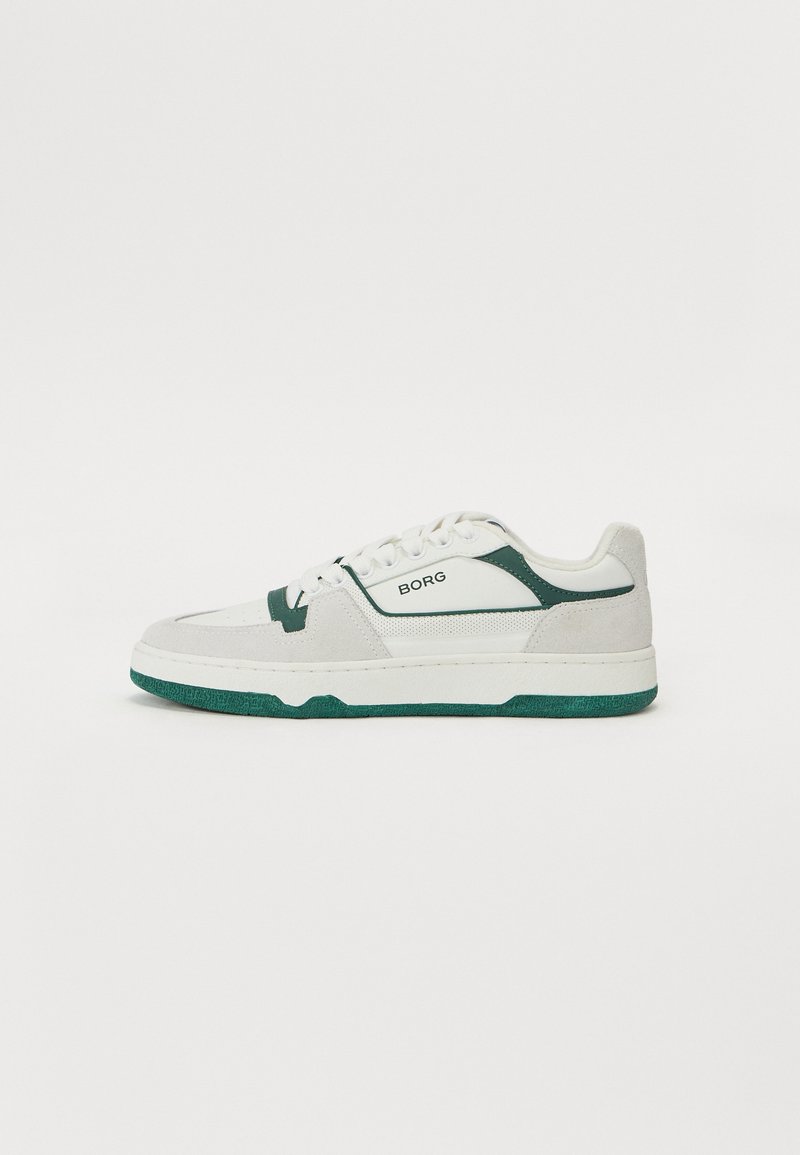 Hvit sneakers med grønne detaljer, laget av lær og semsket skinn. Har en teksturert tunge, flate snørebånd og en tykk gummisåle.