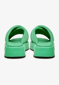 Groene gemoffelde sandalen met afgeronde banden en een dikke platformzool. Gladde textuur met een solide zwarte basis en zonder zichtbare hardware of patronen.