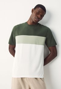 Groen-wit blokkleurig T-shirt van zacht katoen, met een ronde hals en korte mouwen, een gladde textuur en minimale naden.