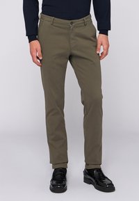 Khaki chinos med en slim fit, tillverkade av bomullstyg. Har en knappstängning och sidofickor; bärs med svarta kostymskor.