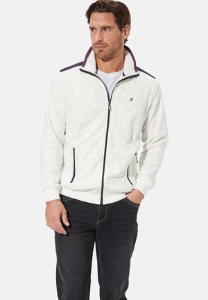 White zip-up jacket with textured fabric, contrasting dark purple collar and shoulder accents, side pockets, and ribbed cuffs and hem.