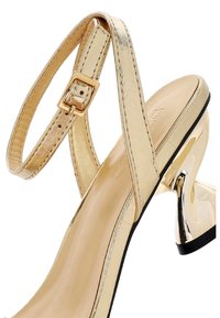Gouden metalen hoge hak sandaal met een gestructureerde strap, verstelbare gespsluiting en een slanke, glanzende hak met een zwarte basis.