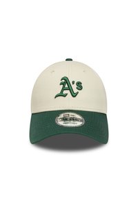 Gorro de lana con corona en color crema y visera verde. Presenta un logotipo bordado en verde de "A's" en la parte frontal. Fabricado con un material textil.