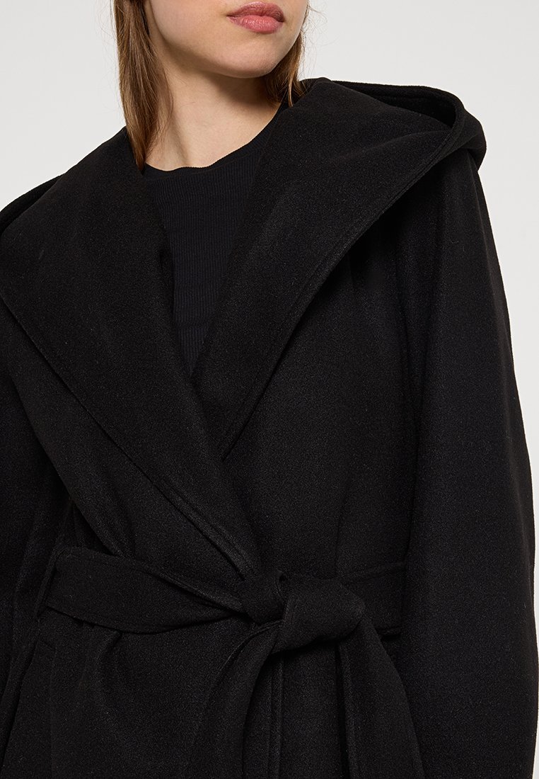 Svart ullblandningskappa med bred krage, bältad midja och långa ärmar, med mjuk textur och minimalistisk design.