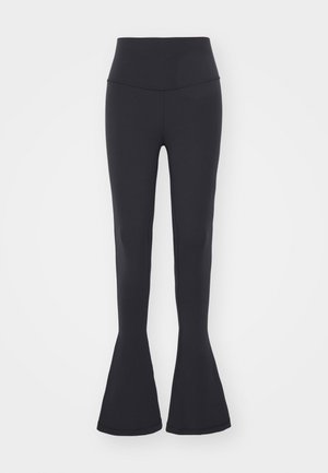 Čierne legíny so širokým pásom, vyrobené z elastického materiálu. Hladký povrch s priliehavým strihom a rozšíreným lemom.