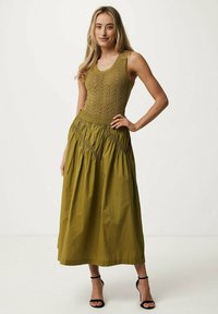 Olivgrön klänning med en stickad, mönstrad byst och en svängd, rynkad kjol. Har en figursydd midja och design i ankellängd.