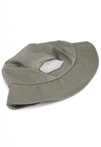 Grön bomullsbucket-hatt med en bred, flexibel skärm och ett sydd band, med en texturerad etikett som visar varumärket.
