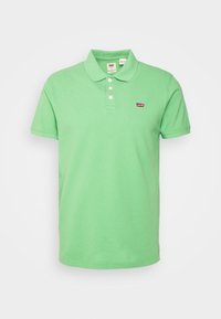 Grön polotröja i bomull med krage, treknapplås, korta ärmar och en liten röd Levi's-logotyp på bröstet.