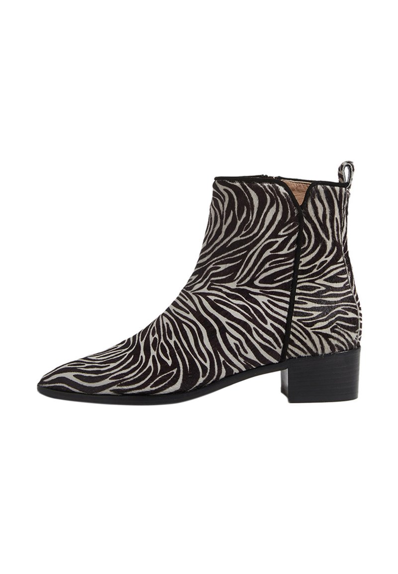 Zebra-print ankelstøvle lavet af blødt stof, med spids tå, lav blokhæl og glatte sorte accenter på siderne og bagpå.