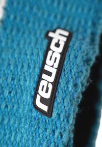Knitted blue gloves featuring a textured fabric, with a black Reusch logo tag attached. The material has a soft, fuzzy appearance.