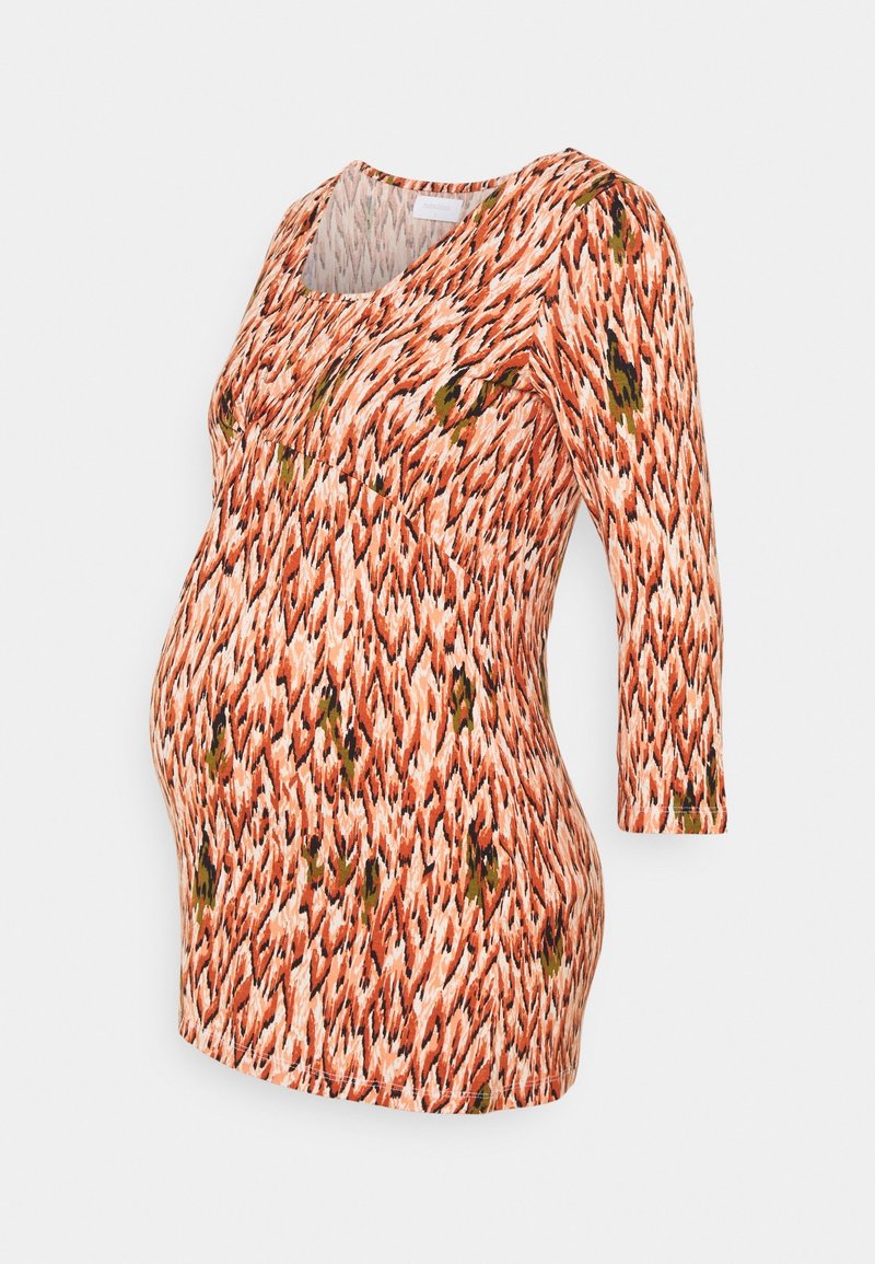 Umstandsbluse aus gemustertem Stoff in Orange, Creme und Grün. Sie hat einen Rundhalsausschnitt und Dreiviertelärmel.