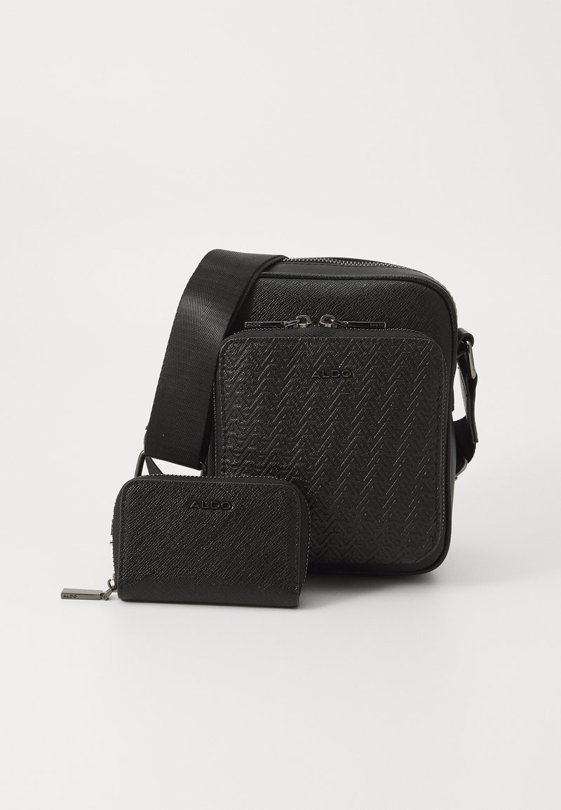 Černá crossbody taška vyrobená z texturovaného materiálu s vzorem herringbone, obsahující hlavní zipovou přihrádku a menší odpovídající peněženku.