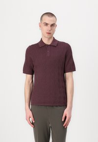 Burgundský pletený polo s krátkymi rukávmi, rebrovaným golierom a geometrickým vzorom; spojený s olivovozelenými nohavicami.