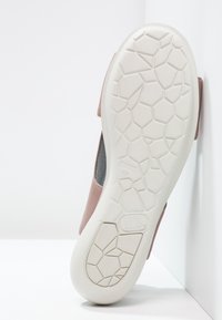Scarpa rosa con suola in gomma testurizzata e motivo a nido d'ape, e parte superiore liscia. Il design presenta lati aperti e un interno imbottito.