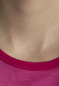 Fuchsia tyg med en mjuk textur har en rund halsringning och en tunn sömad kant, vilket visar en närbild av kragsområdet.