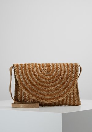 Sac bandoulière rectangulaire en paille tissée avec fermeture à rabat et motif circulaire dans des tons marron naturel sur une surface blanche.