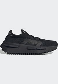 Black athletic shoe featuring a knitted upper, textured detailing, and chunky rubber sole with ridges. Includes functional laces and logo accents.