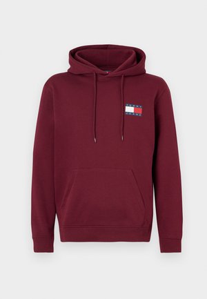 Bordová mikina s predným vreckom, s kapucňou na sťahovanie a potlačeným logom v modrej, červenej a bielej farbe na ľavej strane hrude. Mäkká textúra látky.