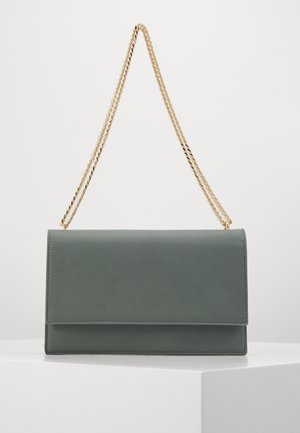 Bolso de hombro rectangular de cuero gris con correa de cadena tono dorado, colocado sobre un pedestal blanco contra un fondo liso.