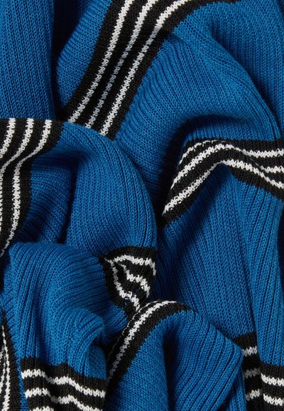 Tessuto a maglia blu con motivi a righe nere e bianche. La texture è morbida con un aspetto accogliente e stratificato.