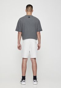 T-shirt gris à manches courtes avec une coupe droite, associé à un short gris clair ; les deux vêtements offrent une coupe décontractée et une texture douce.