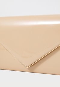 Clutch de sobre de charol en tono nude con un acento en tono dorado a lo largo del borde. Superficie elegante y lisa con un cierre de solapa agudo y angular.