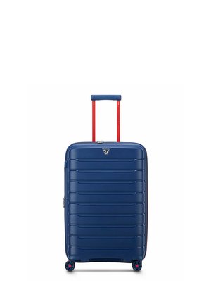 Valigia rigida blu navy con scanalature orizzontali, manico telescopico rosso e quattro piccole ruote nere con rifiniture rosse.