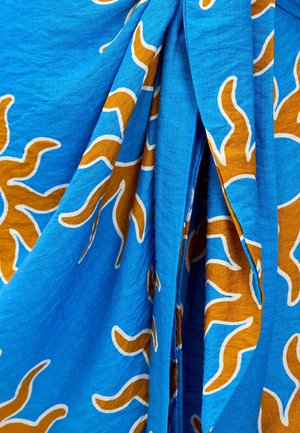 Tissu bleu avec un motif tourbillonnant marron et blanc. La texture paraît douce, avec des plis visibles et une chute légère.