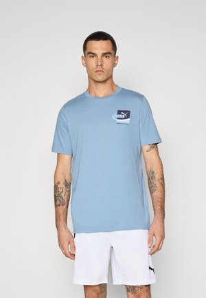 Light blue cotton t-shirt with short sleeves, round neckline, and a small Puma logo on the chest. Worn with white shorts.