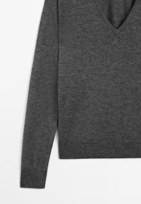 Pull gris foncé à manches longues avec col en V, poignets et ourlet côtelés, présenté à plat sur fond blanc.