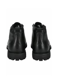 Las botas negras de cuero hasta el tobillo presentan un perfil bajo, punta redondeada, forro texturizado y suelas de goma resistentes con patrones de tracción distintivos.