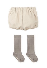 Shorts bouffants texturés beige avec taille élastique, associés à des chaussettes grises côtelées montantes avec un logo près de la manche.