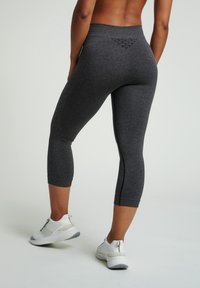Szare, wysokie legginsy capri z fakturowanymi akcentami i bocznymi szwami. Połączone z białymi butami sportowymi z szarymi detalami.