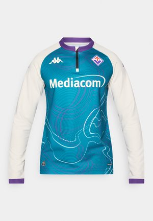Tricou sport cu mânecă lungă, în culori teal și crem, cu un model valuri, accente mov și fermoar frontal. Logo-ul este afișat proeminent.