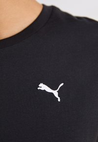 Tricou din bumbac negru cu guler rotund, având un logo brodat alb al unei pume săltând pe partea stângă a pieptului.
