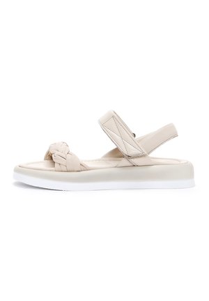 Light beige sandals with a knotted strap and adjustable ankle band, featuring a thick, contrasting white sole for comfort and stability.