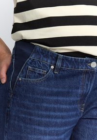 Denimjeans med en mørkeblå vask, der har et klassisk design med fem lommer, sølvfarvede knapper og en blød talje for komfort.